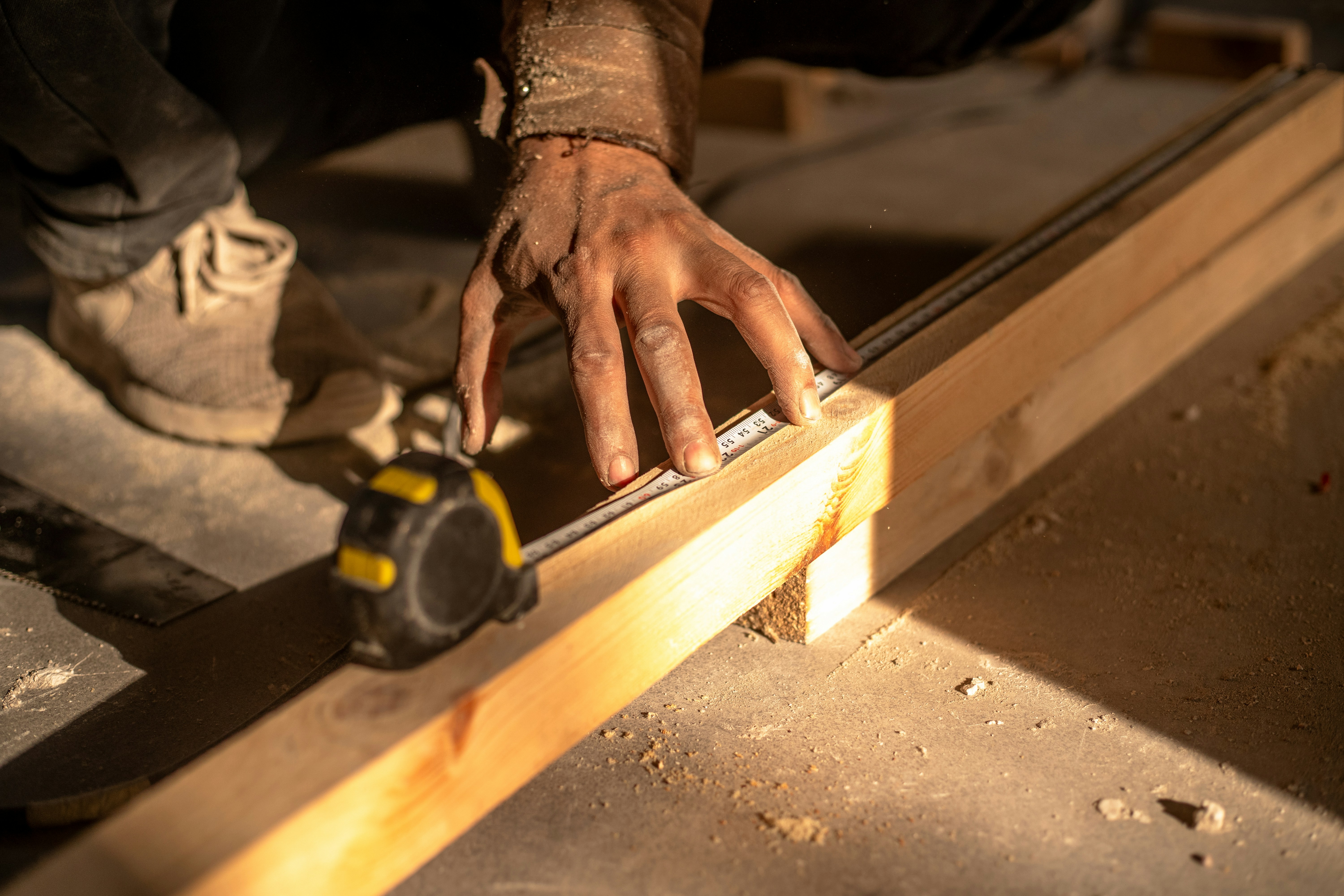Craftsman measuring lumber on site